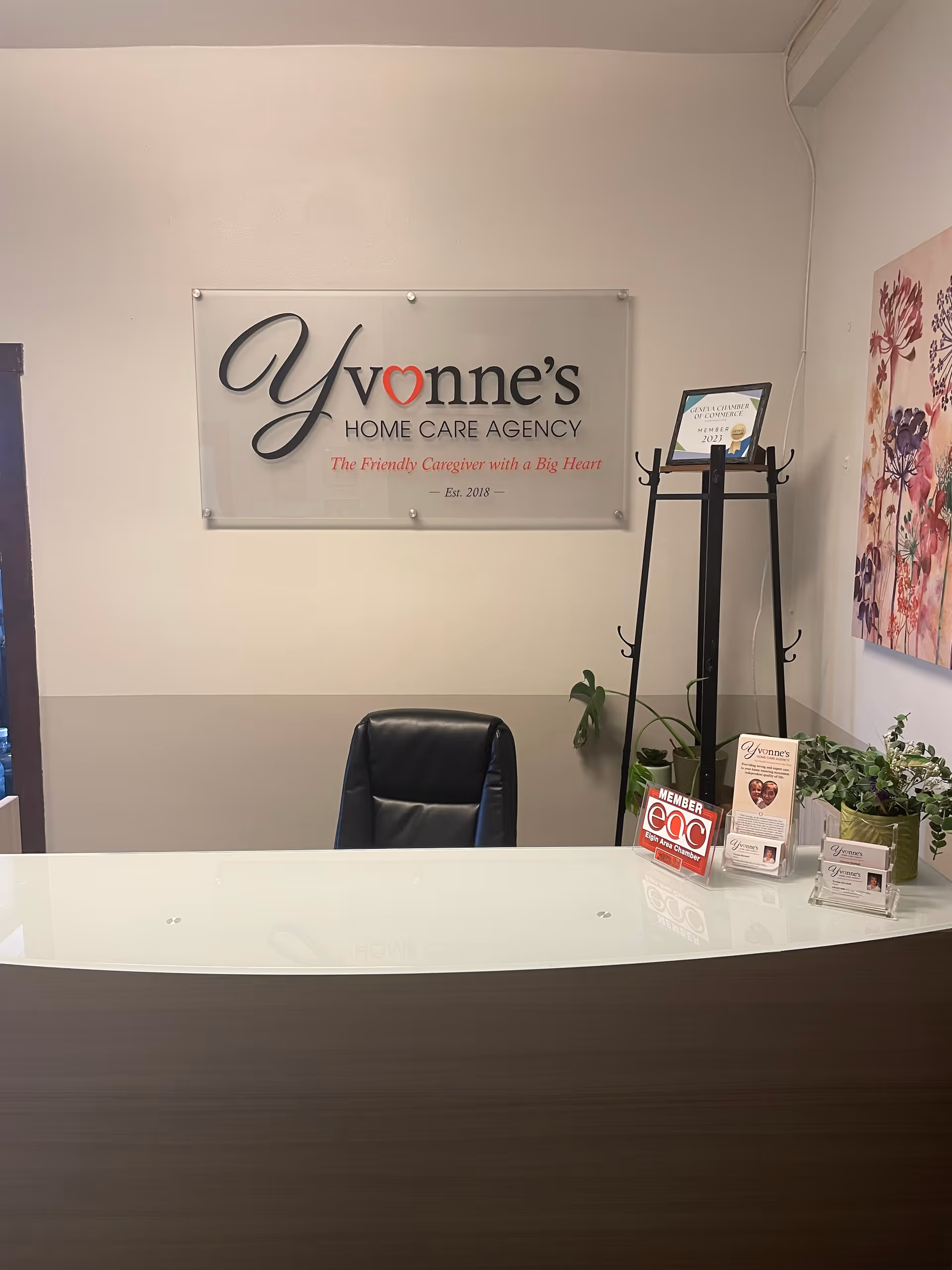 Reception desk in a home care agency lobby with a sign and plants.