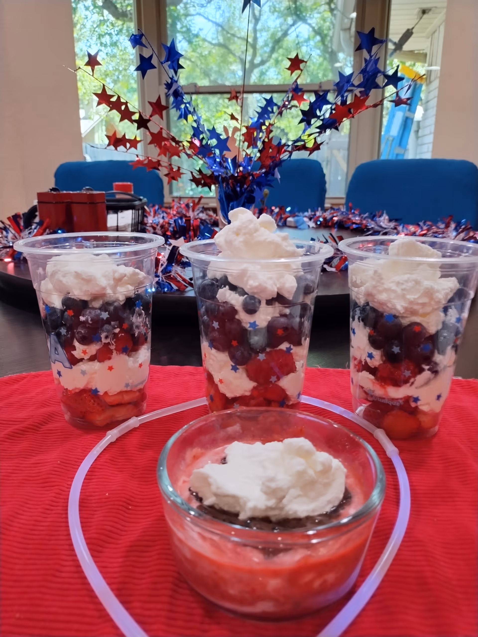 Dessert cups with berries and whipped cream on a red table with star centerpiece