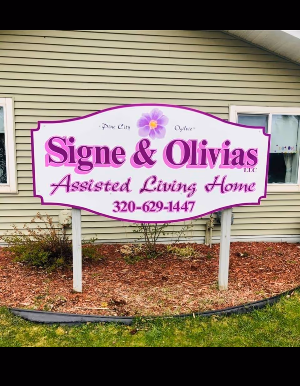 Front yard sign for Signe & Olivias Assisted Living Home on beige siding.