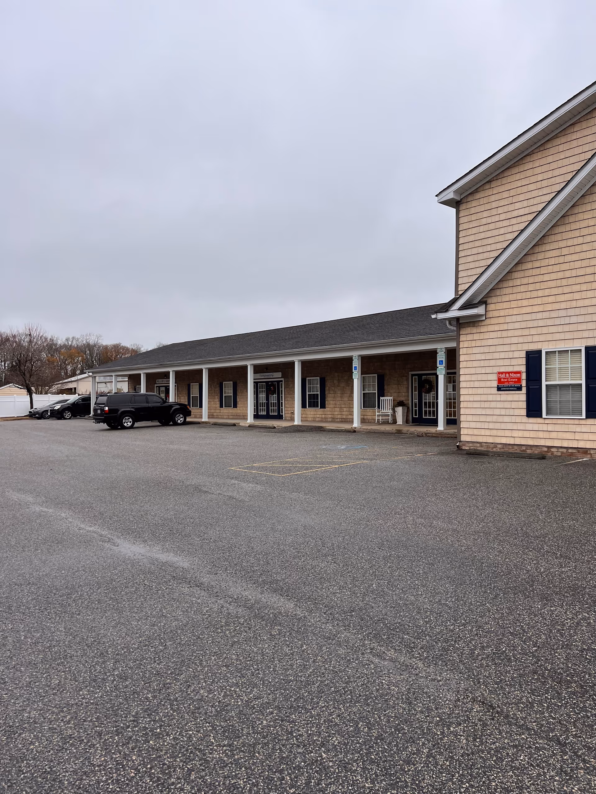 Single-story beige brick senior care facility with columns, front entrances, and a spacious parking lot.