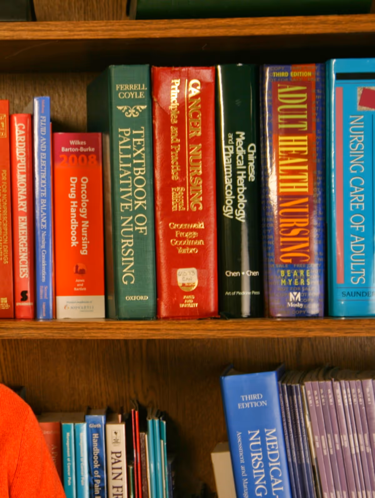 Colorful medical textbooks lined on a wooden bookcase in a quiet interior.