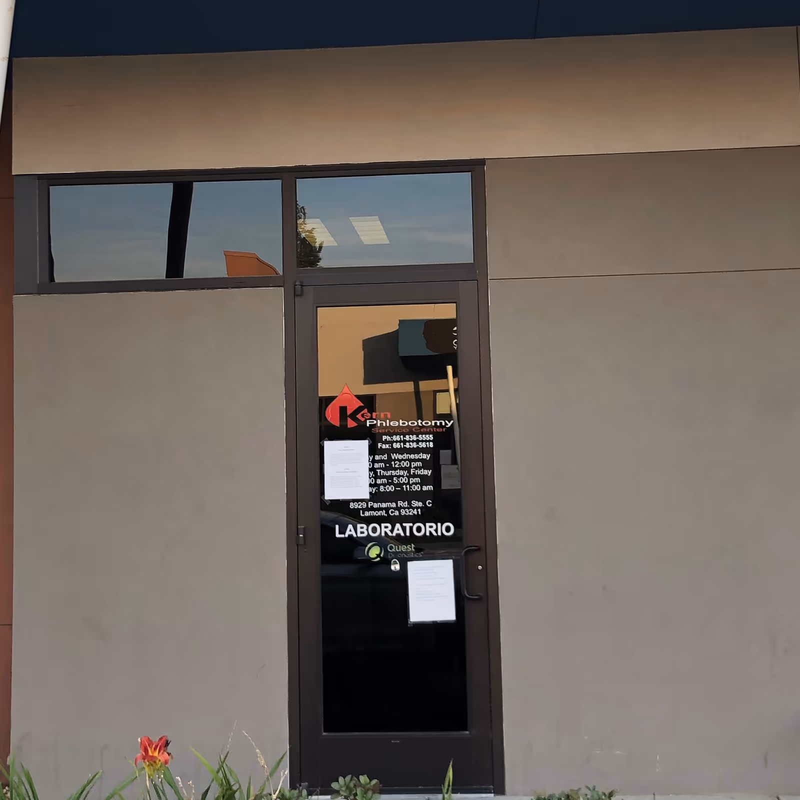 Exterior door displaying Kern Phlebotomy signage on a gray building facade.