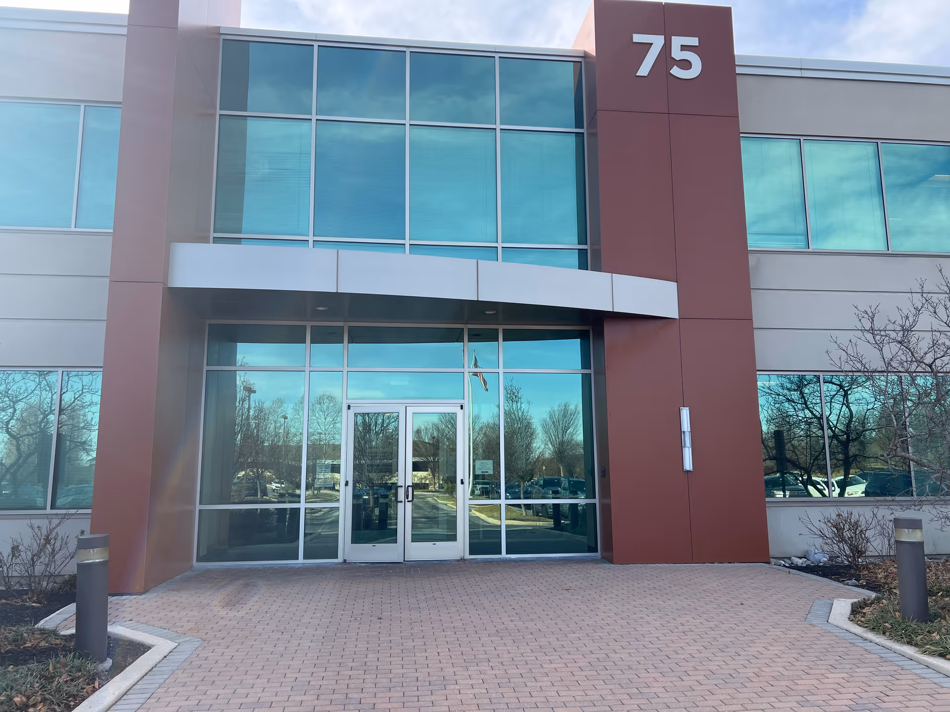 Modern facility entrance with glass doors and a large 75 sign.