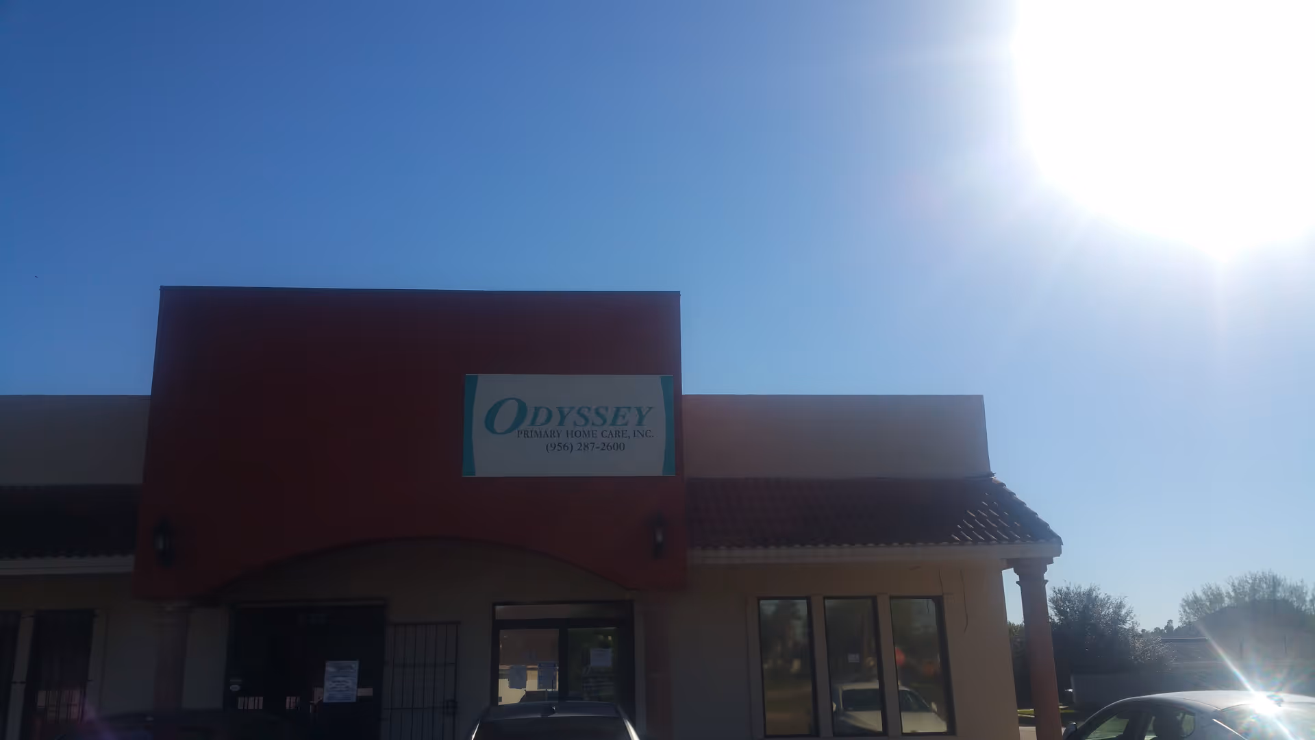 Front exterior of Odyssey Primary Home Care building with sign and sunny sky.