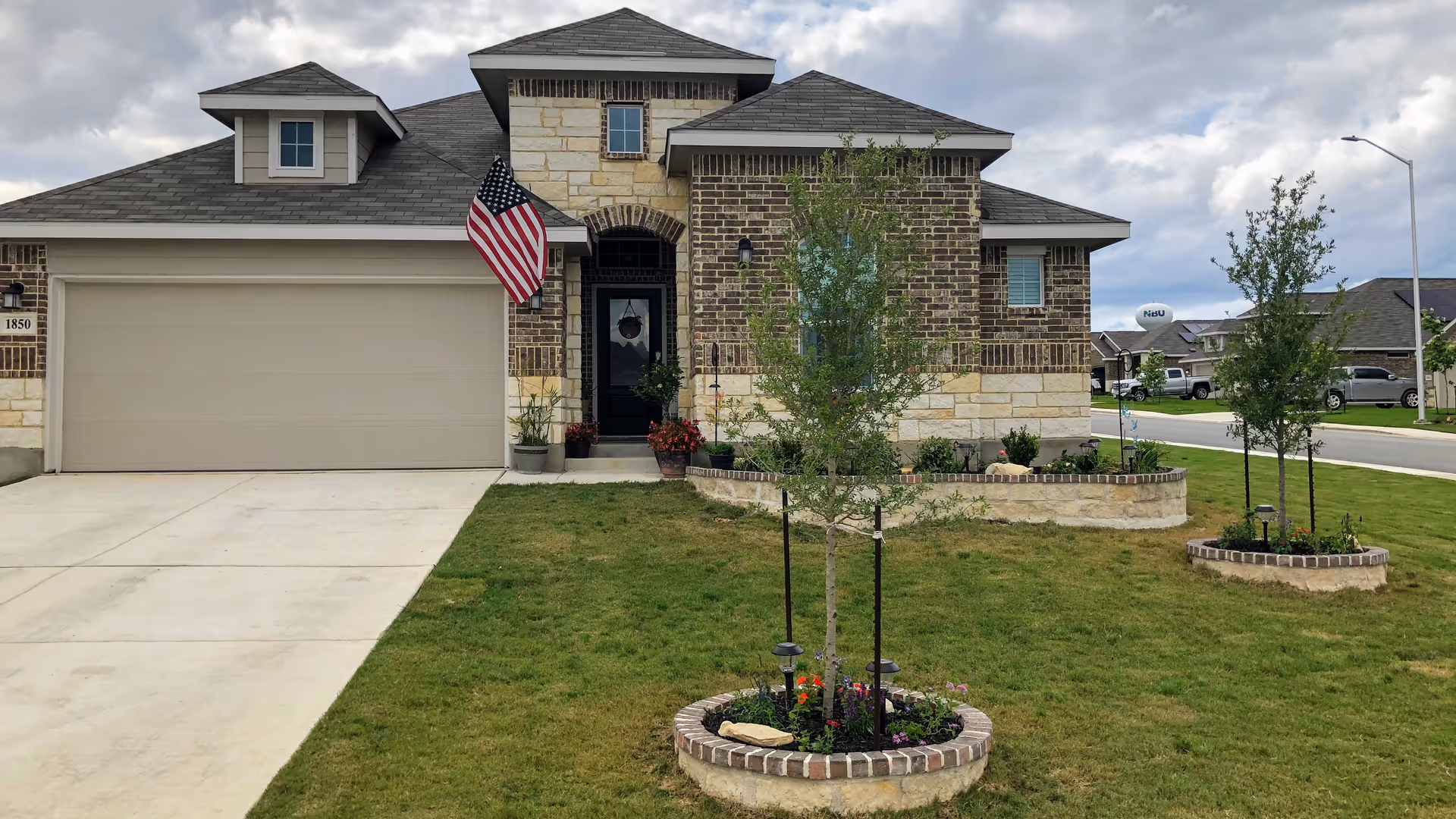 Front view of a brick-and-stone care home with landscaping and an American flag.