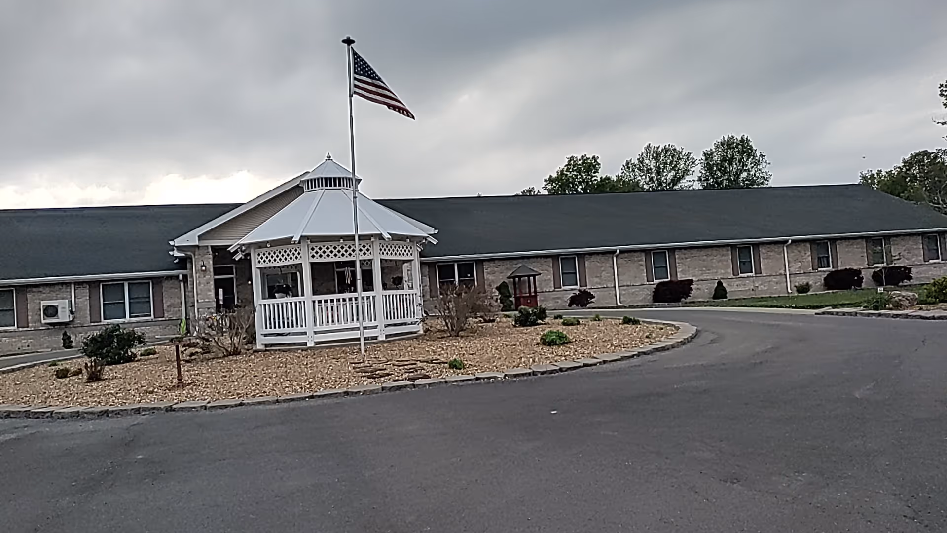 Single-story senior living facility with a white gazebo near a circular driveway.