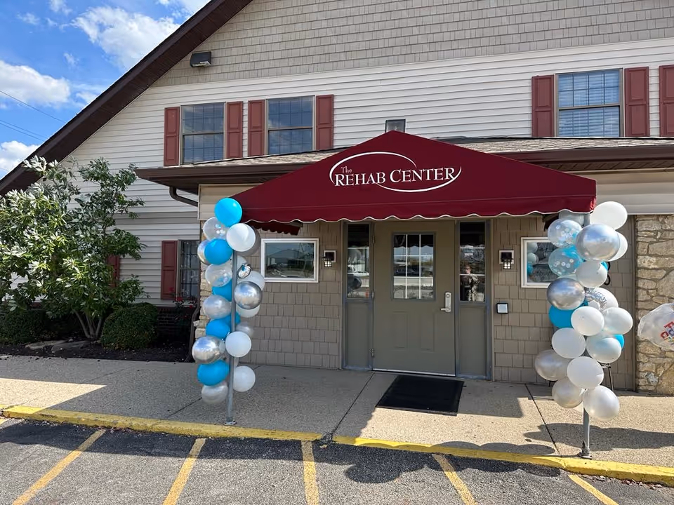Exterior entrance with maroon canopy and balloon decorations at The Rehab Center.