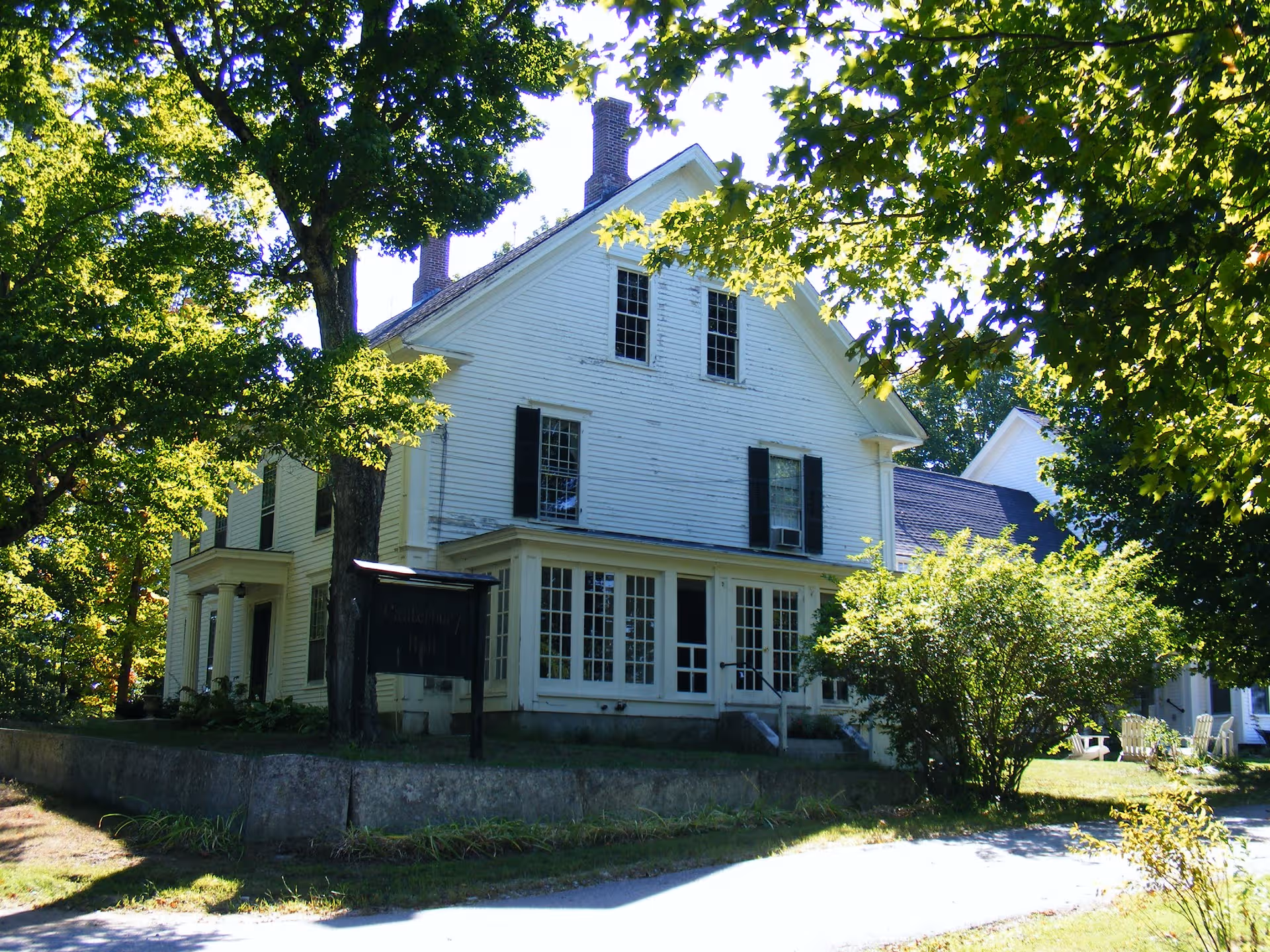 White two-story house exterior with black shutters and surrounding trees