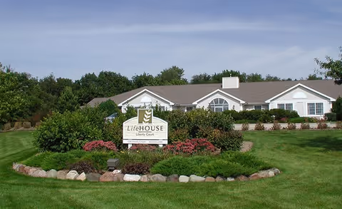 Front view of Liberty Court building with manicured lawn and circular flower bed.