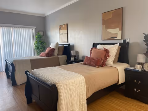 Two twin beds with beige comforters in a bright senior living bedroom.