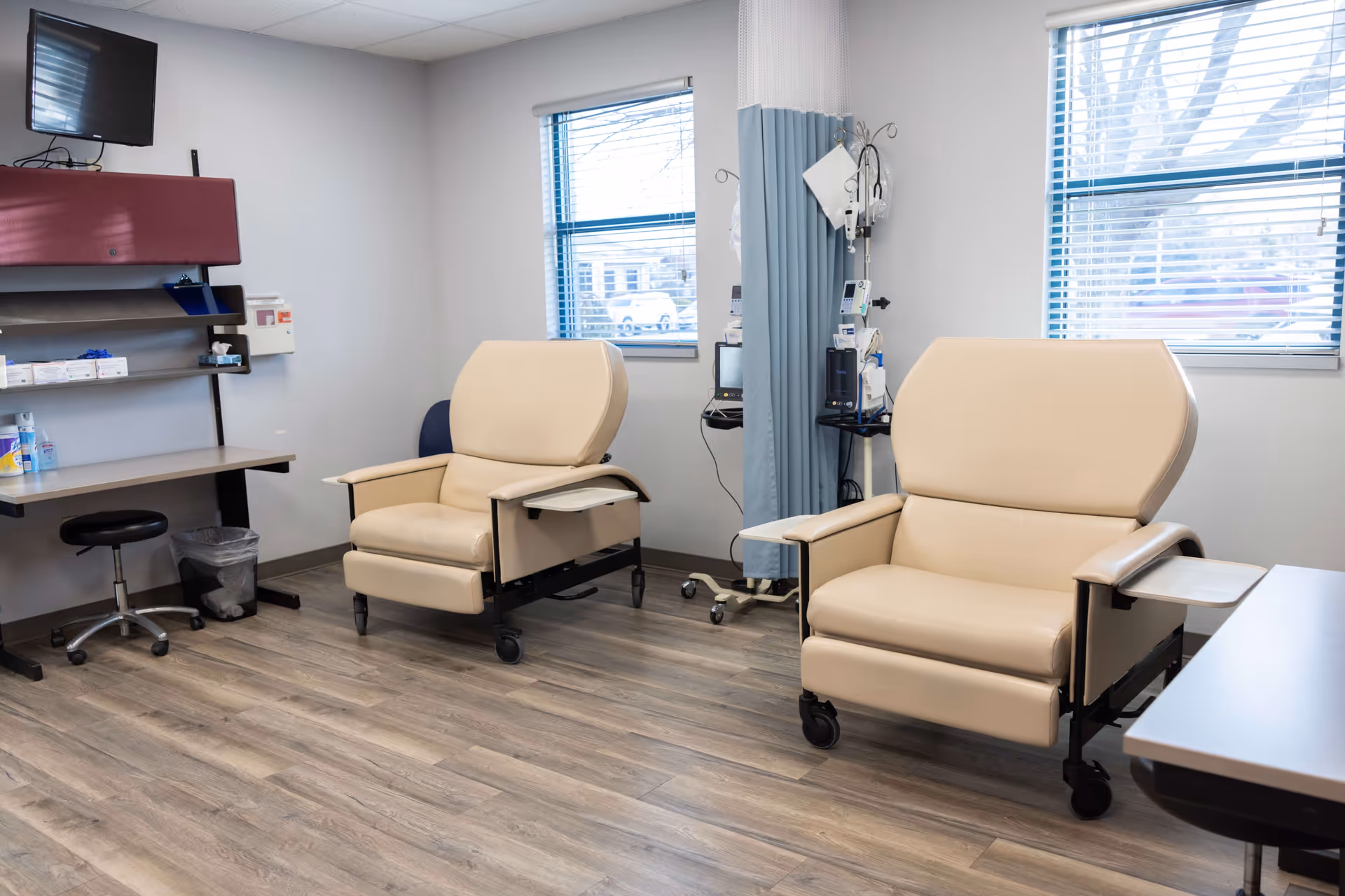Two beige recliner chairs and medical equipment in a clean, well-lit treatment room.