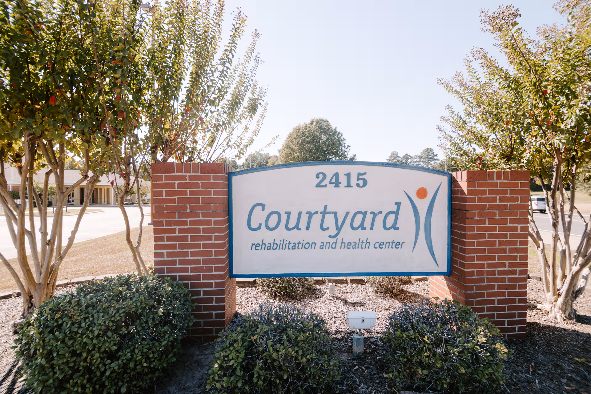 Brick sign for Courtyard rehabilitation and health center at entrance, with landscaping.