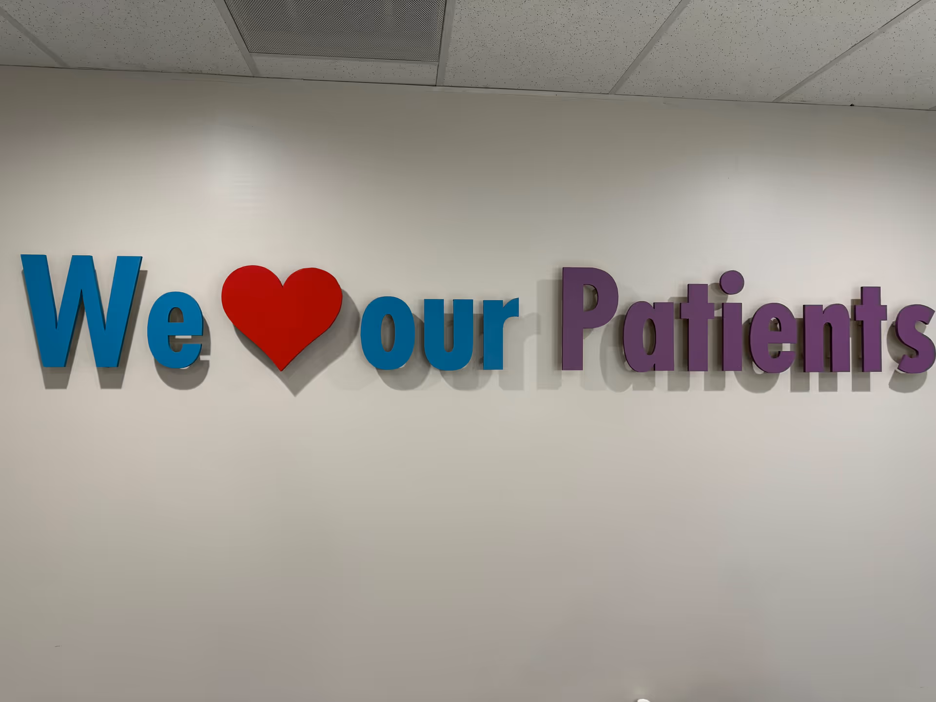 Interior wall sign with colorful 3D letters reading 'We heart our Patients'.