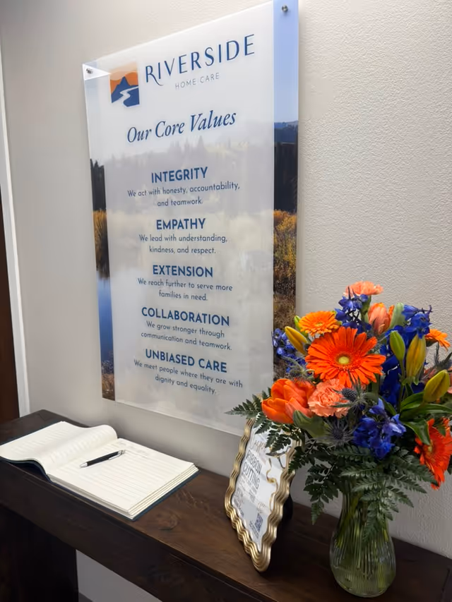 Signboard reading Riverside Home Care with core values beside a bouquet.