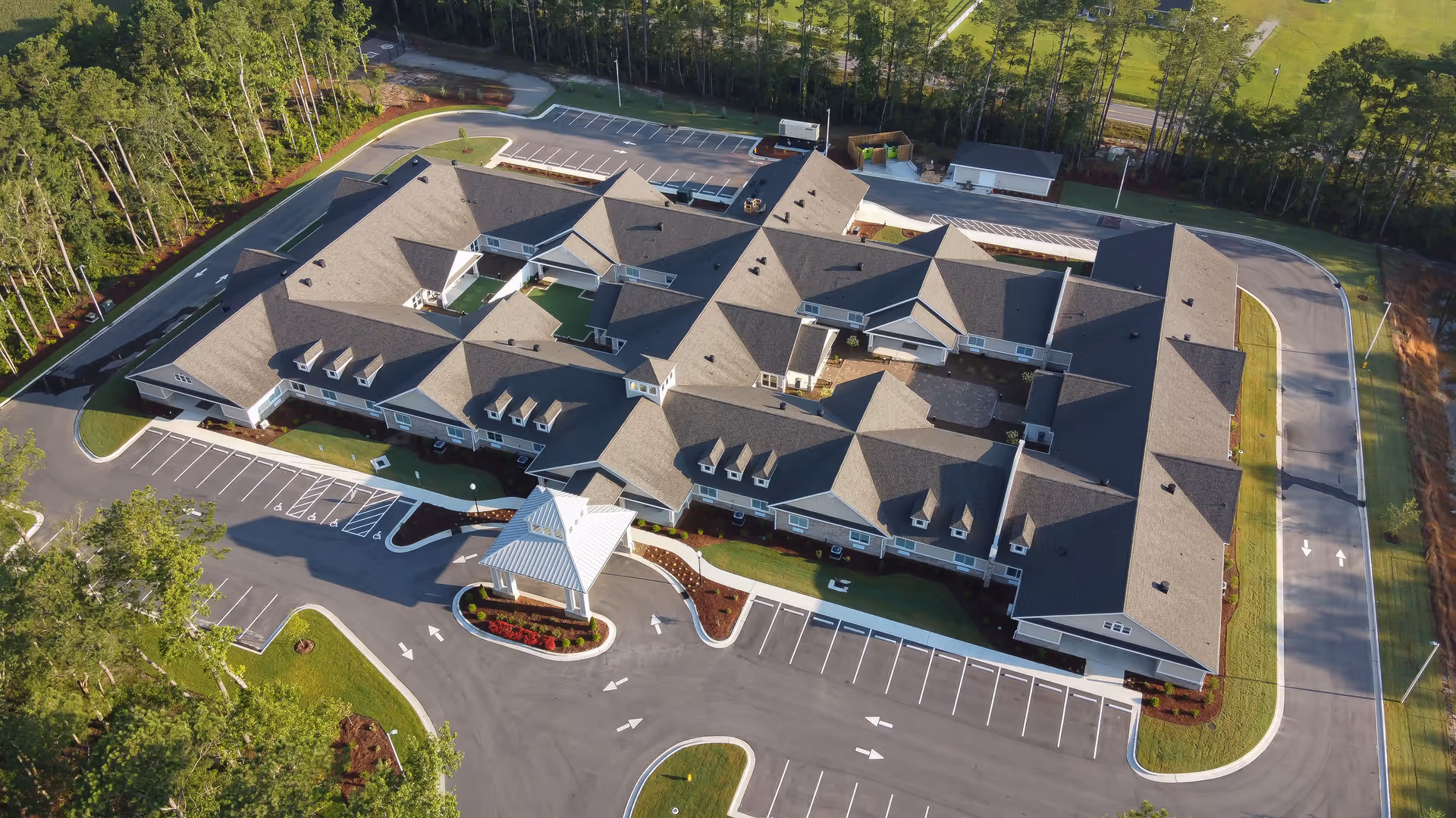 Aerial view of Coastal Pointe Assisted Living and Memory Care building with parking and trees.