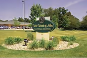 Exterior view of West Woods of Niles Nursing Center sign amid landscaped lawn