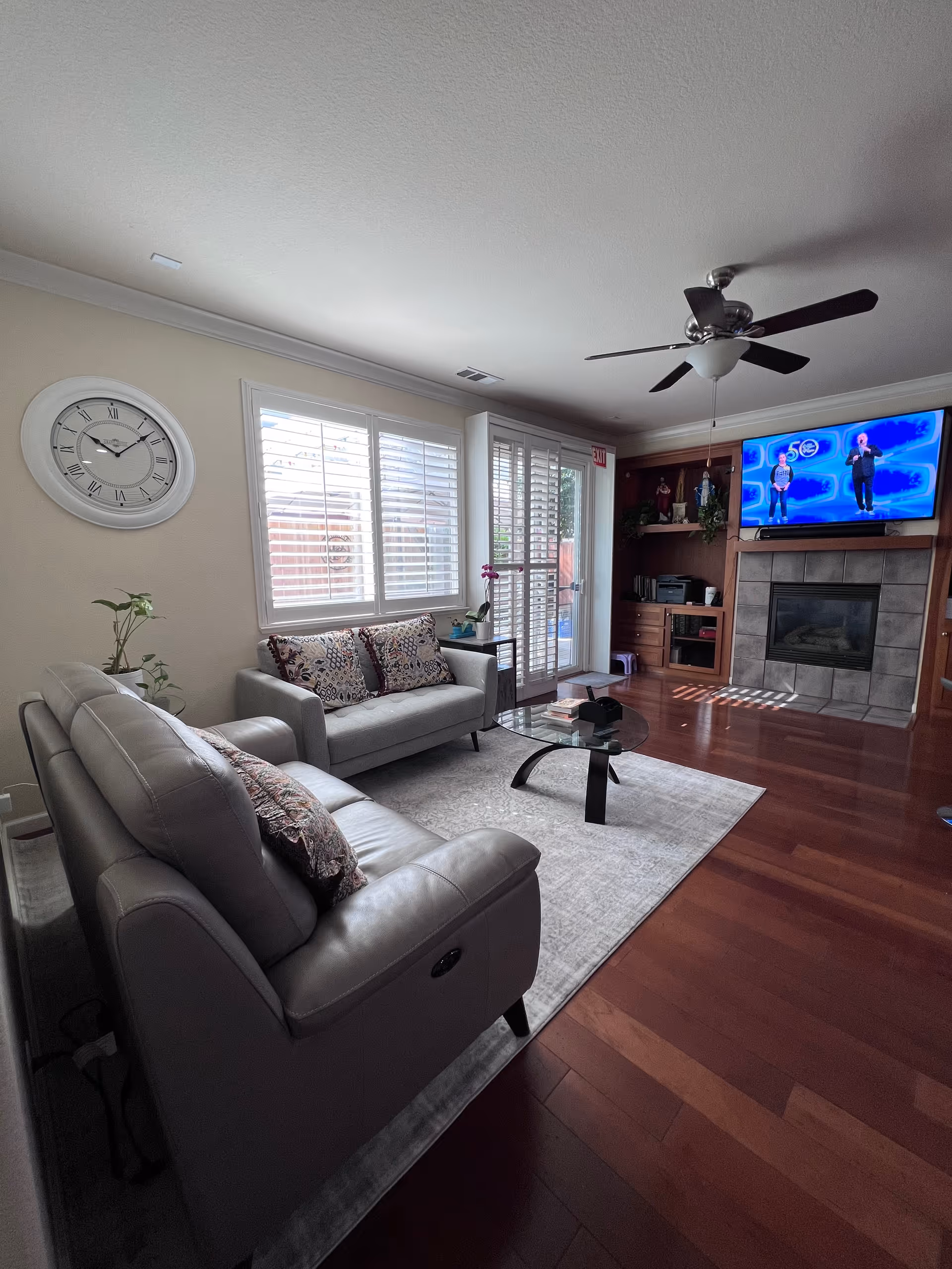 Cozy living room with leather sofas, glass coffee table, fireplace, and mounted TV.