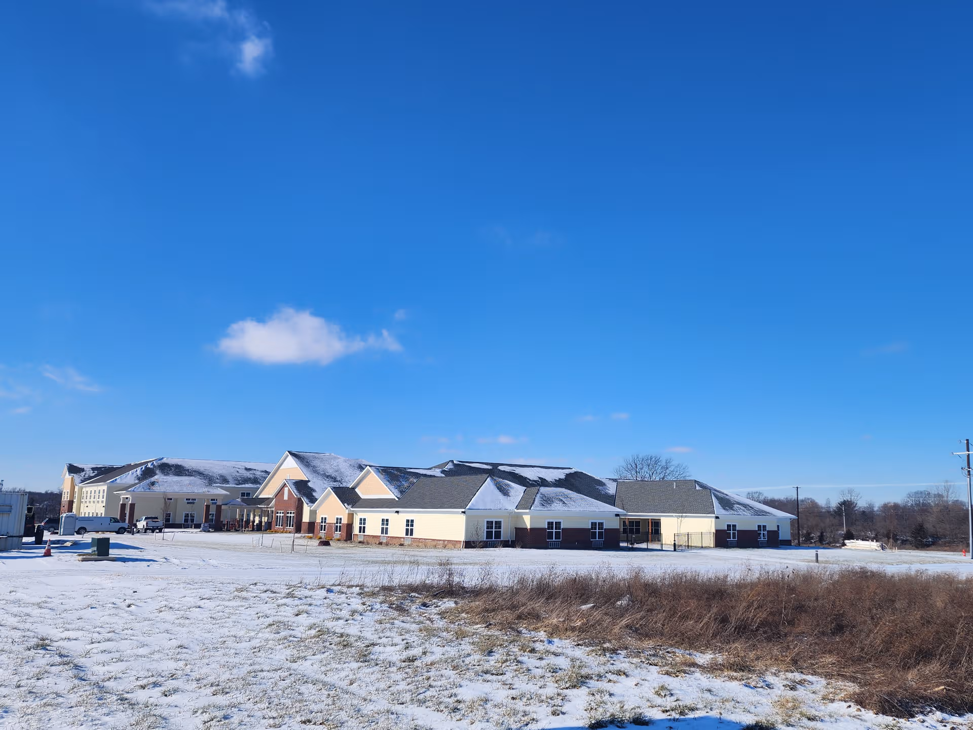 Snow-dusted senior living facility with connected wings and a bright blue sky.