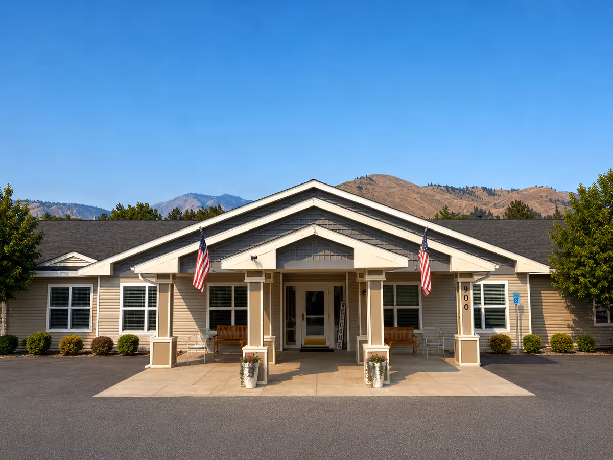 Front view of RiverWest senior living entrance with flags and mountains behind