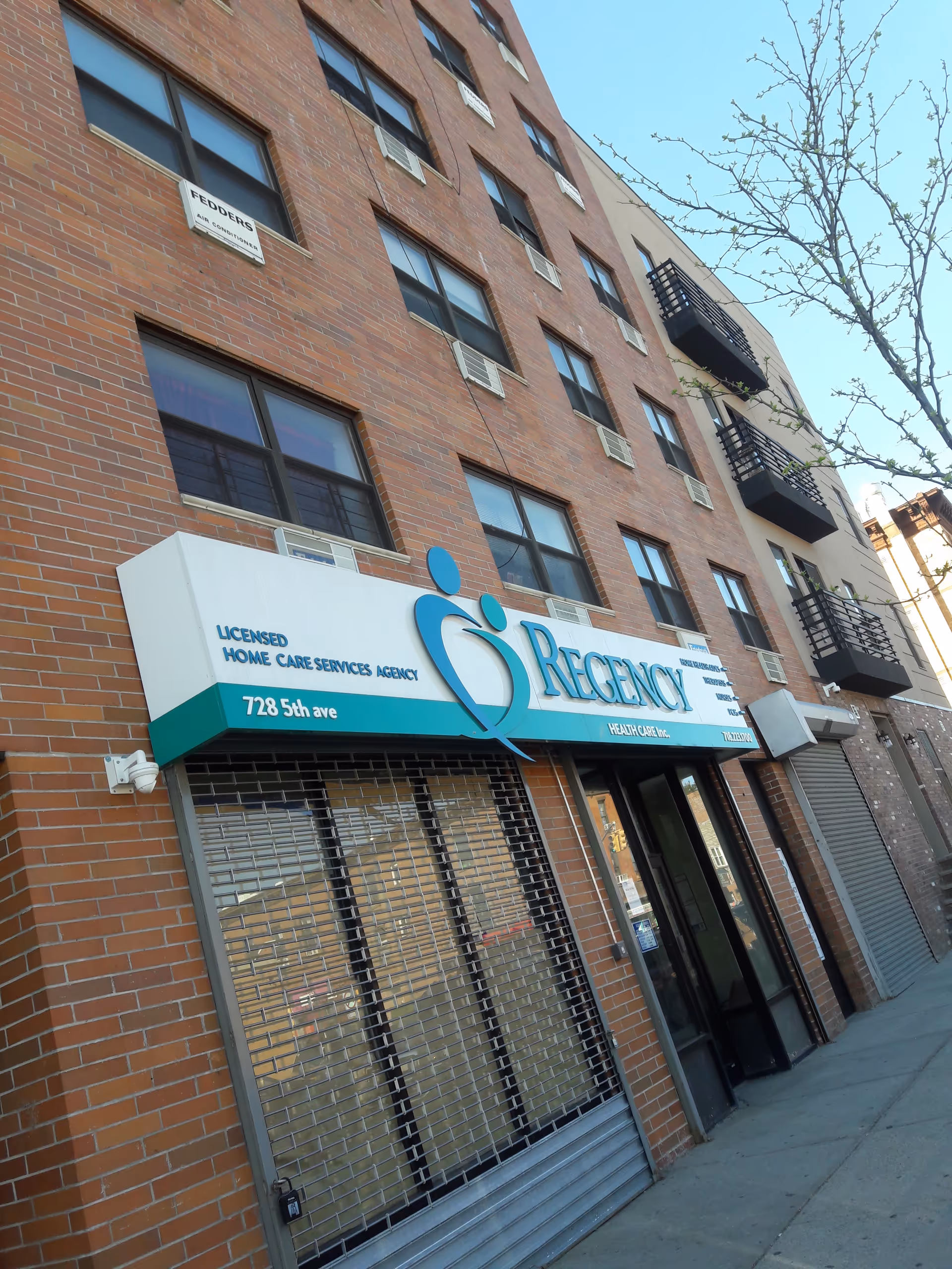 Brick building with Regency Health Care storefront and closed metal security shutters on ground floor.