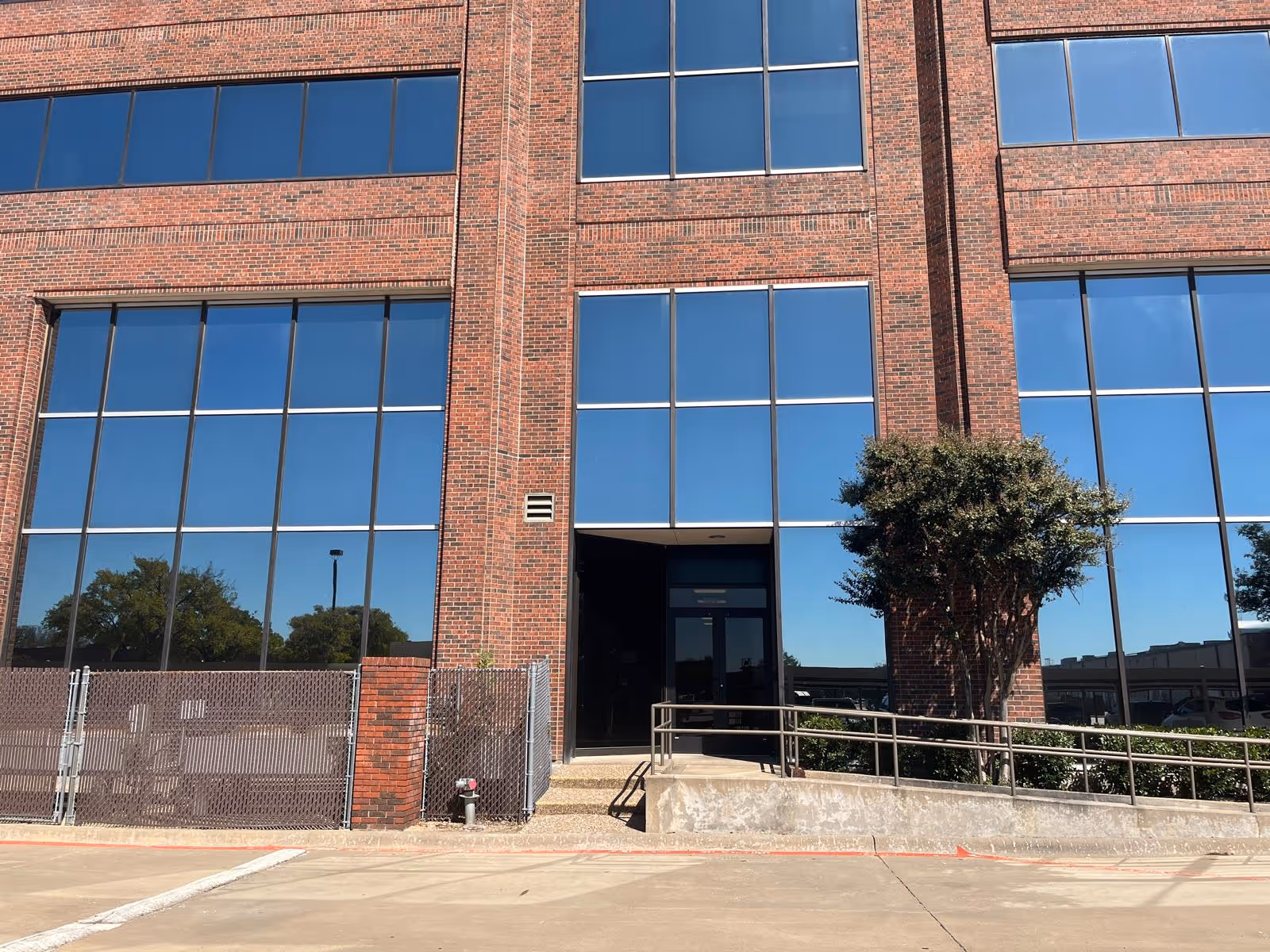 Brick building exterior with large glass windows and central entryway.