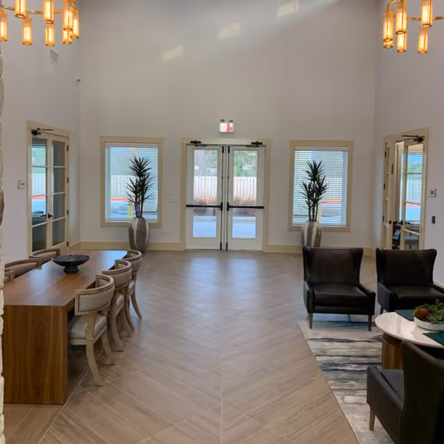 Bright senior living lobby with dining table, chairs, and lounge seating.