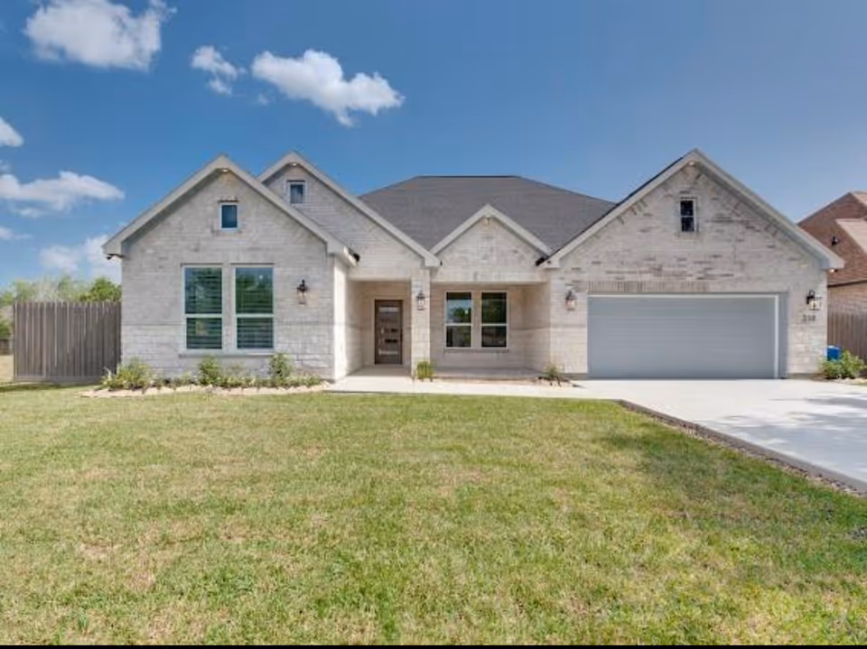 Single-story stone-exterior senior living residence with a manicured lawn and two-car garage.