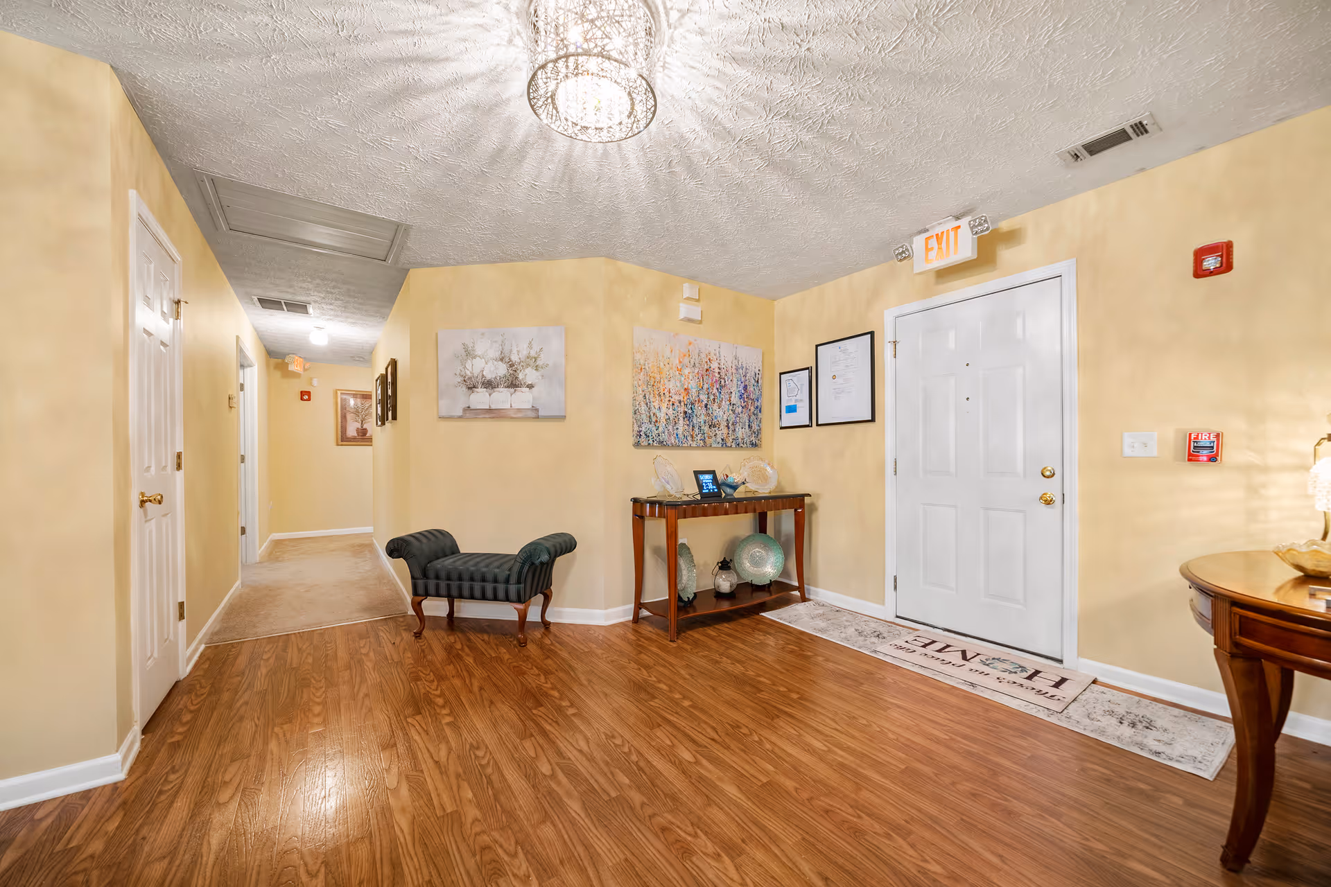 Warm beige hallway with bench, console table, artwork, and a front door.