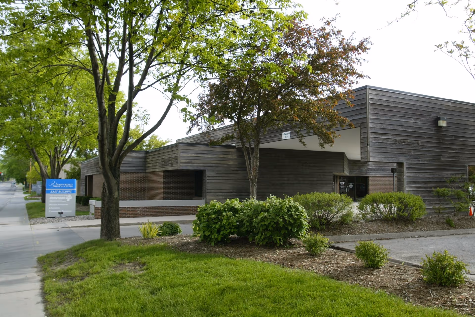 Exterior of Mary Greeley Home Health Services building with trees and shrubs.
