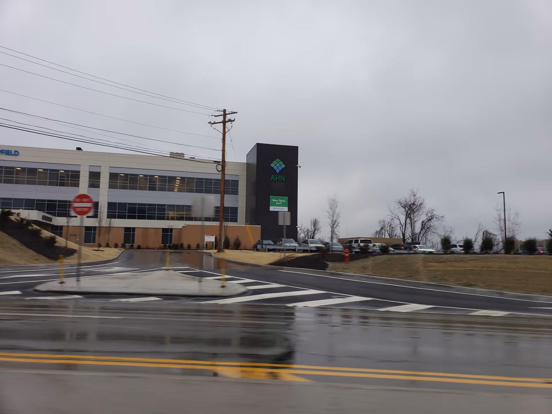 Exterior view of AHN Outpatient Center at Hempfield Neighborhood Hospital with parked cars.