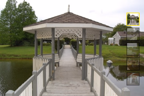 Wooden gazebo on a pier-like walkway over water leading to manicured lawn and trees