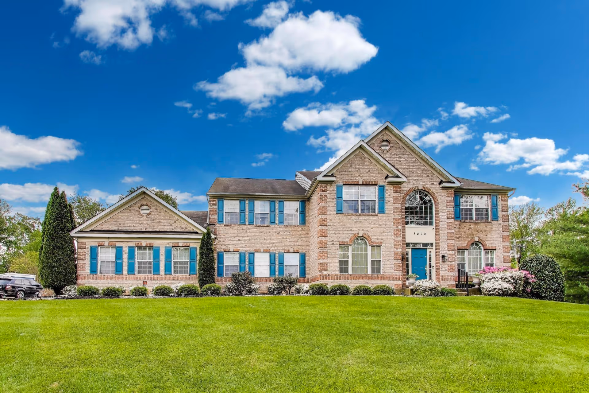Brick assisted-living building with blue shutters sits on a well-kept green front lawn.