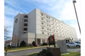 A large beige senior living facility with multiple stories, a driveway, and landscaped entrance.