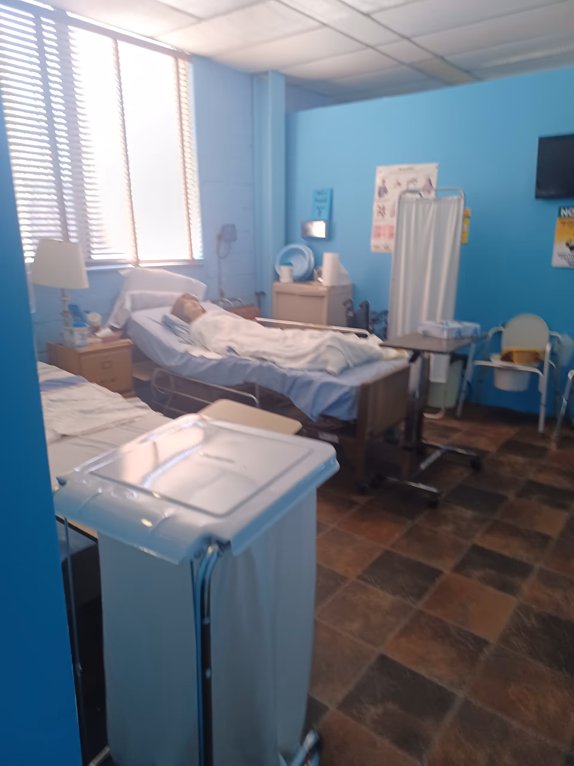 Hospital-style patient bed in a blue-walled room with medical equipment.