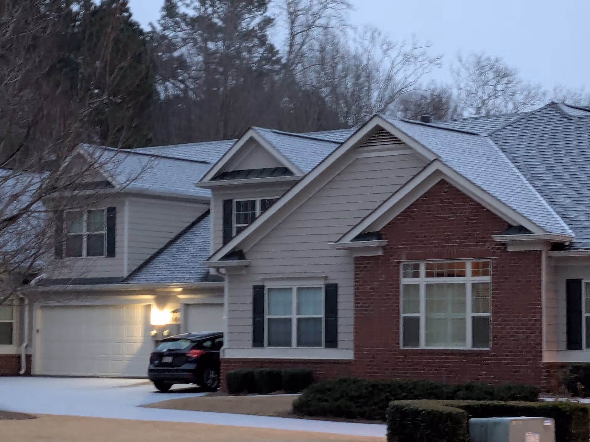 Residential senior living building exterior with brick facade, siding, and a parked car by the driveway.