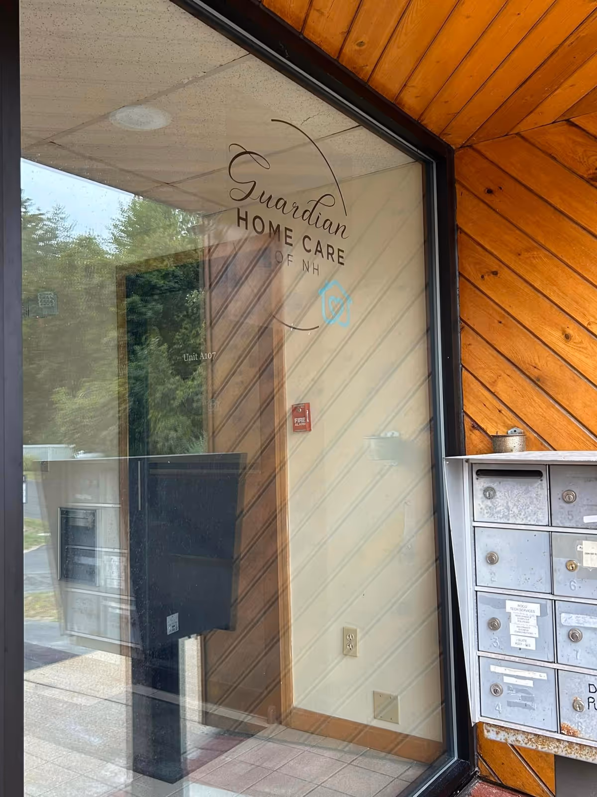 Glass entrance door shows Guardian Home Care of NH logo with wood-paneled exterior.