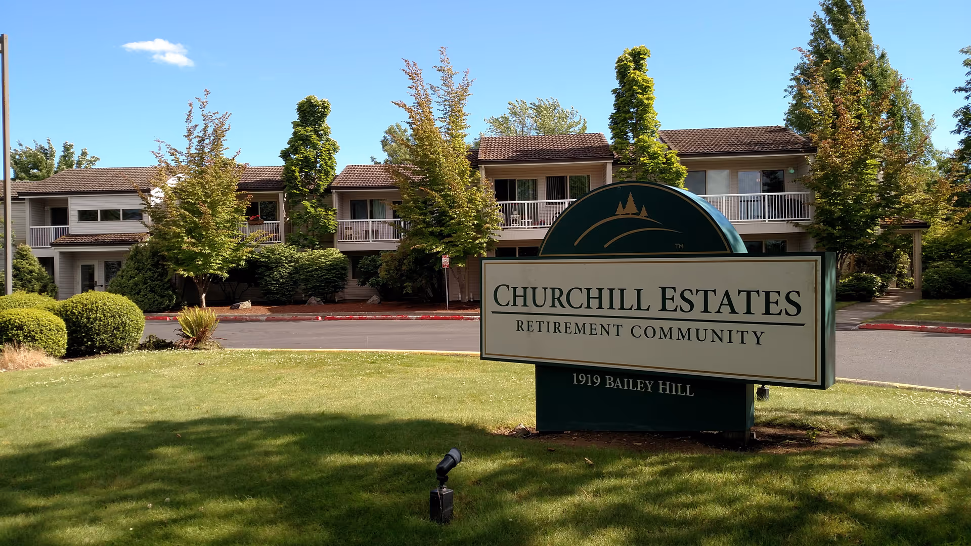 Exterior view of Churchill Estates Retirement Community with a large sign and building.