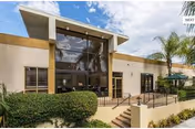 Front view of Alexandria Care Center exterior featuring a glass entrance and palm trees.