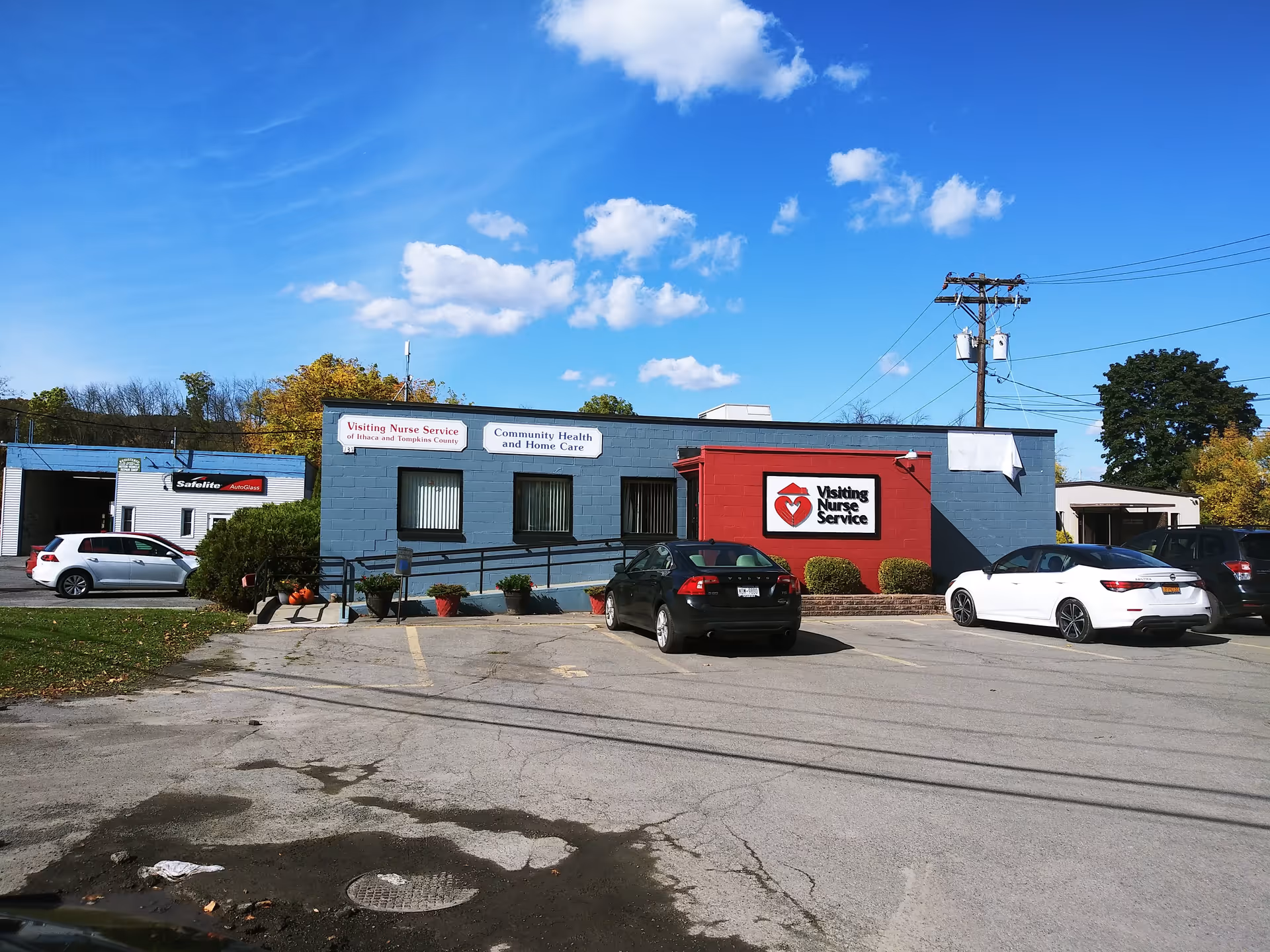 Exterior view of a blue building with Visiting Nurse Service signage and parked cars.