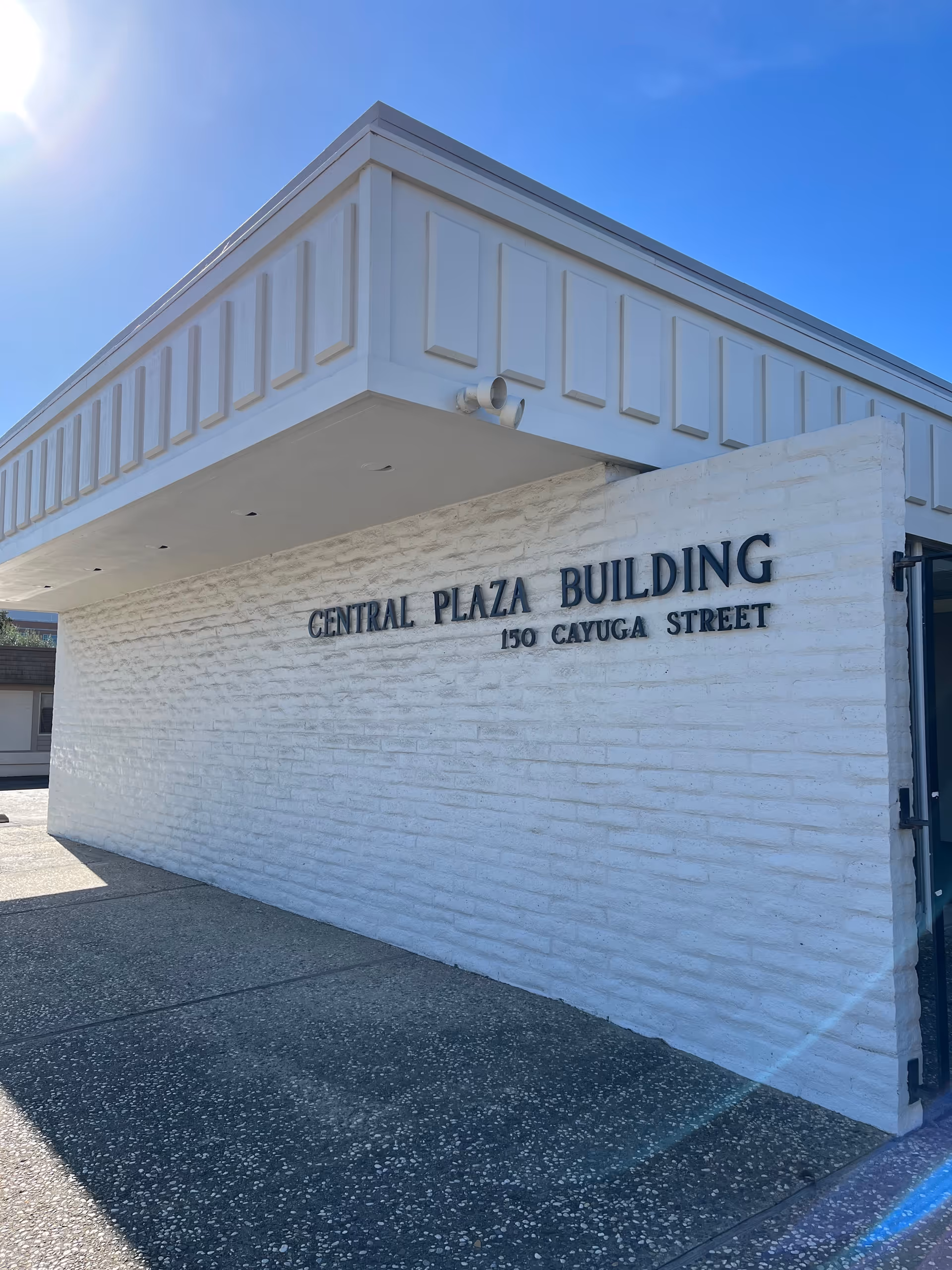 White brick building exterior with Central Plaza Building sign and address 150 Cayuga Street