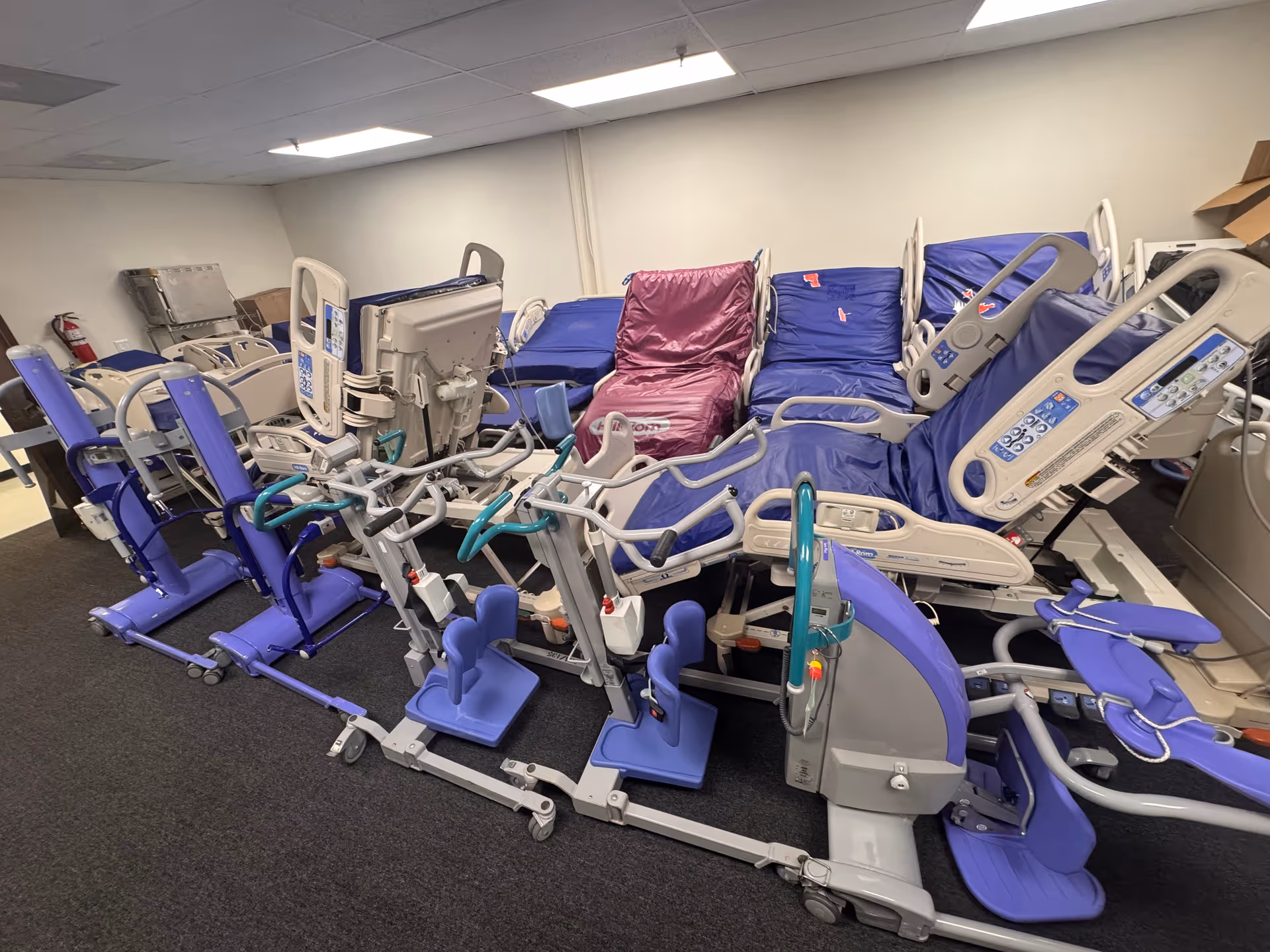 A storage room filled with multiple hospital beds and medical equipment stacked together.