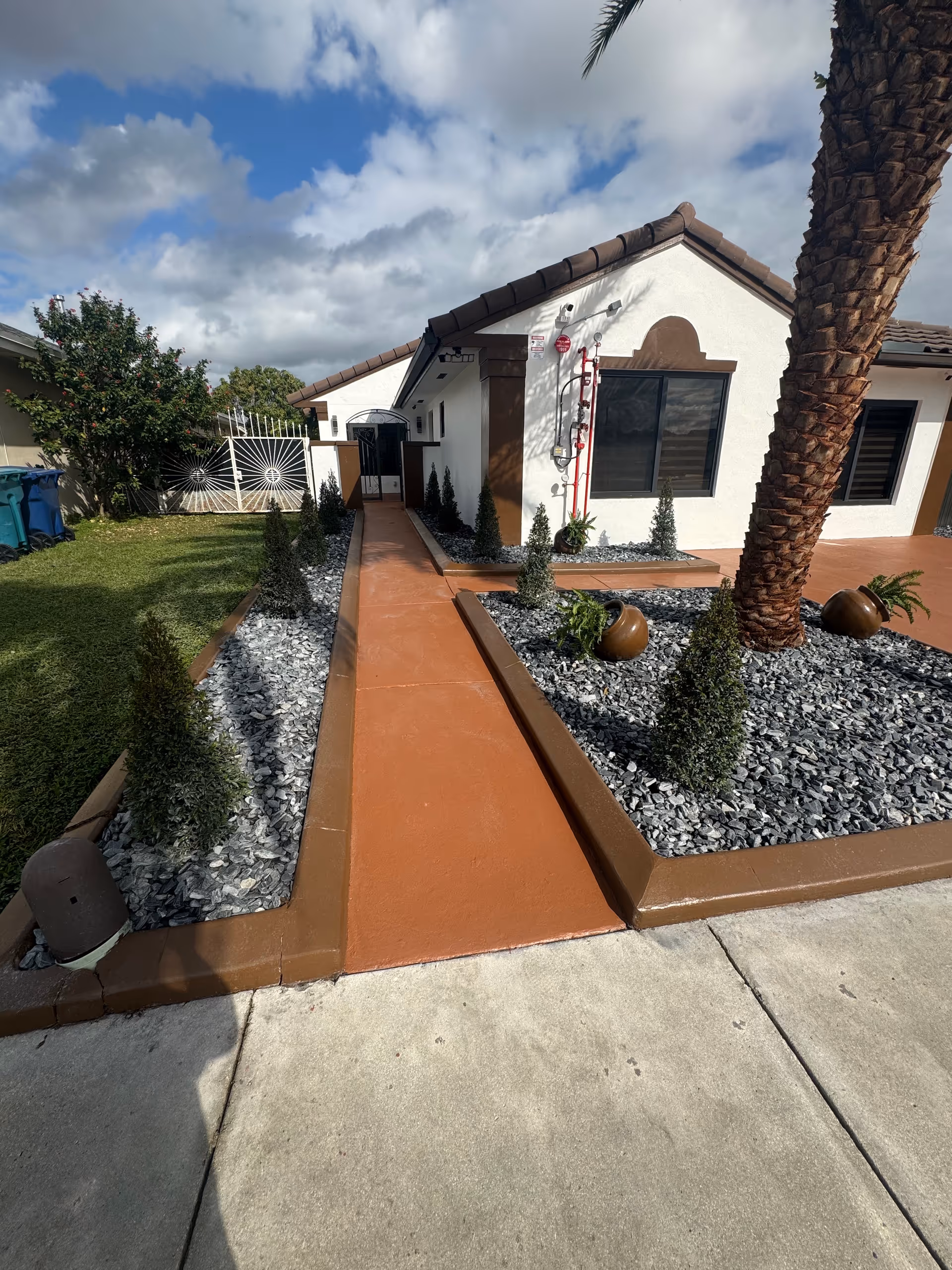 Front exterior of a single-story white facility with an orange walkway and landscaped rocks.