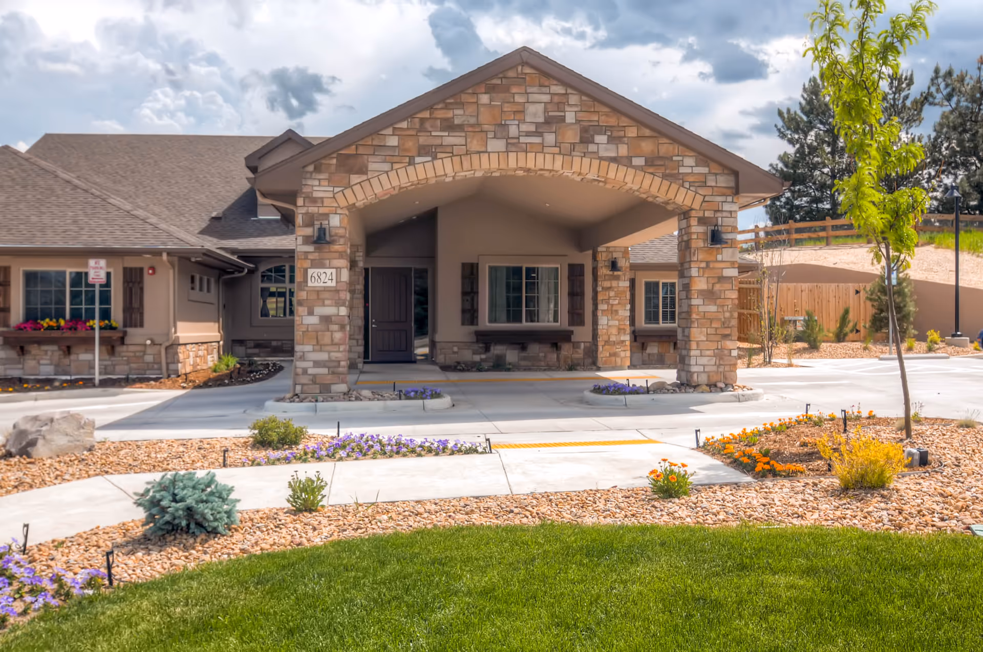 Front view of Rocky Mountain Assisted Living Chestnut facility with stone entry arch and landscaped grounds.