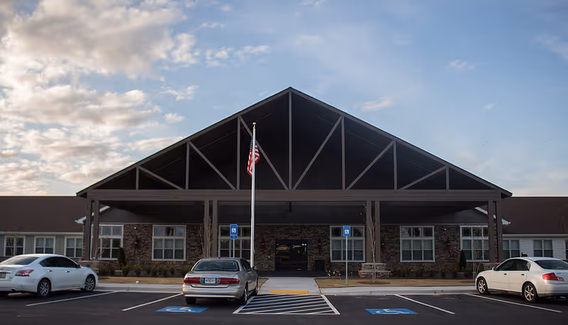 Front view of Phoenix at Lake Joy facility with porte-cochere entrance and parked cars.