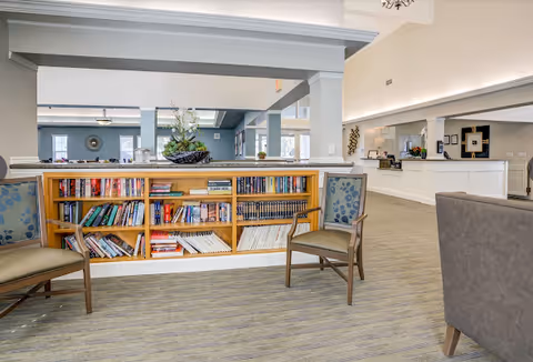 Bright Lakeside Landings lobby with a book-filled low shelf, chairs, and a reception desk.