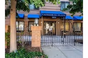 Front entrance of Cathedral Plaza with a blue awning, gated courtyard, and brick façade.