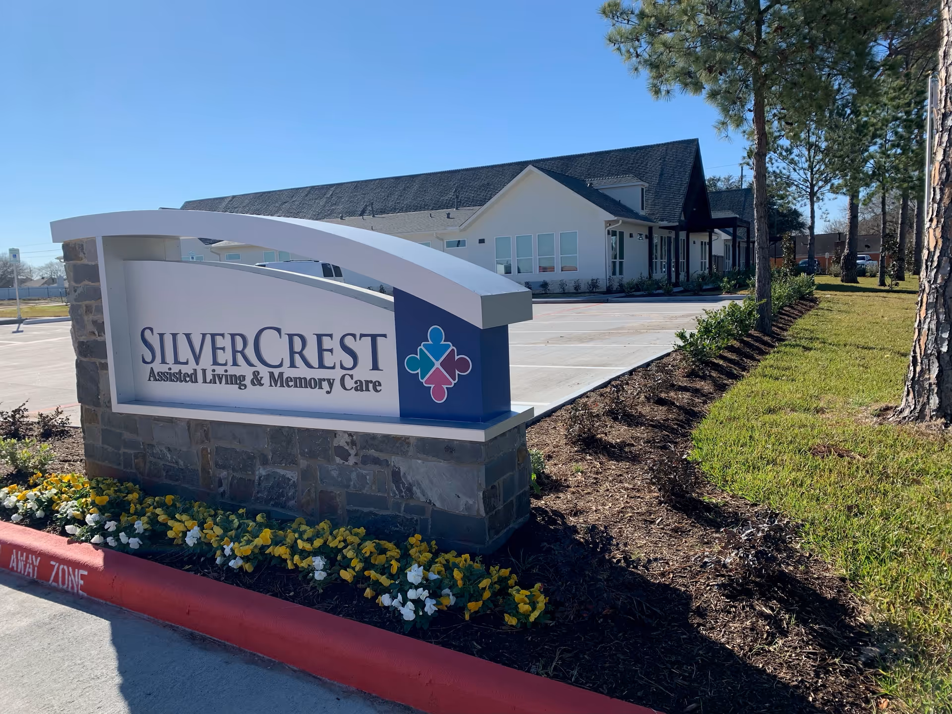 Entrance sign reading 'SilverCrest Assisted Living & Memory Care' with the facility building and landscaped grounds in the background.