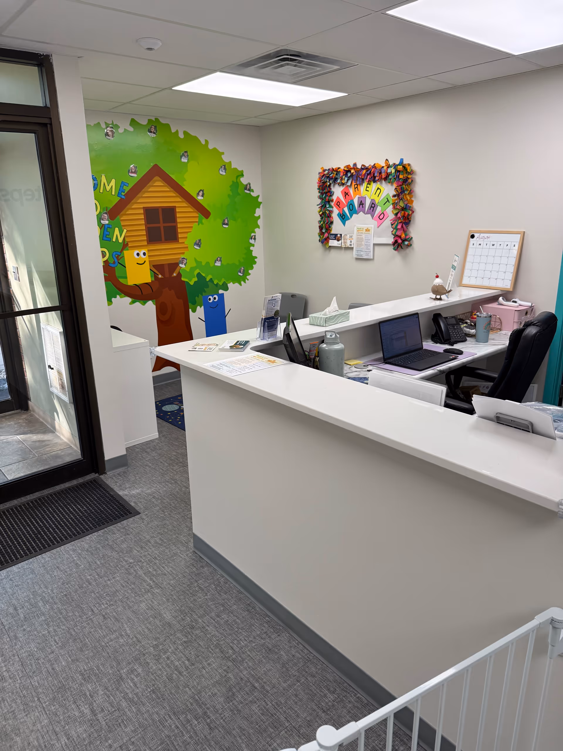 Reception desk in a bright ABA therapy center with colorful murals and office equipment.