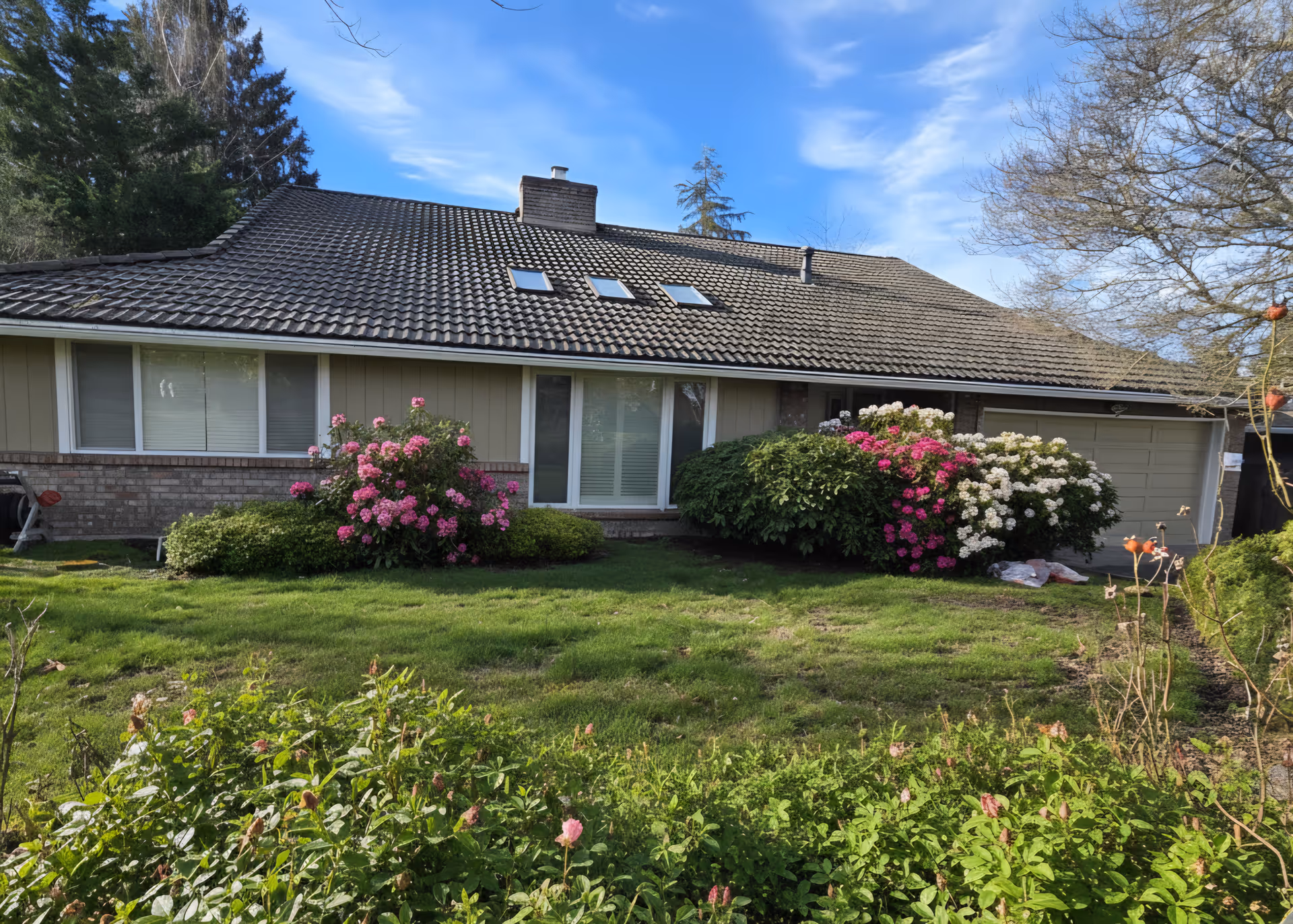 Single-story senior living home exterior with colorful flowering shrubs near the windows.
