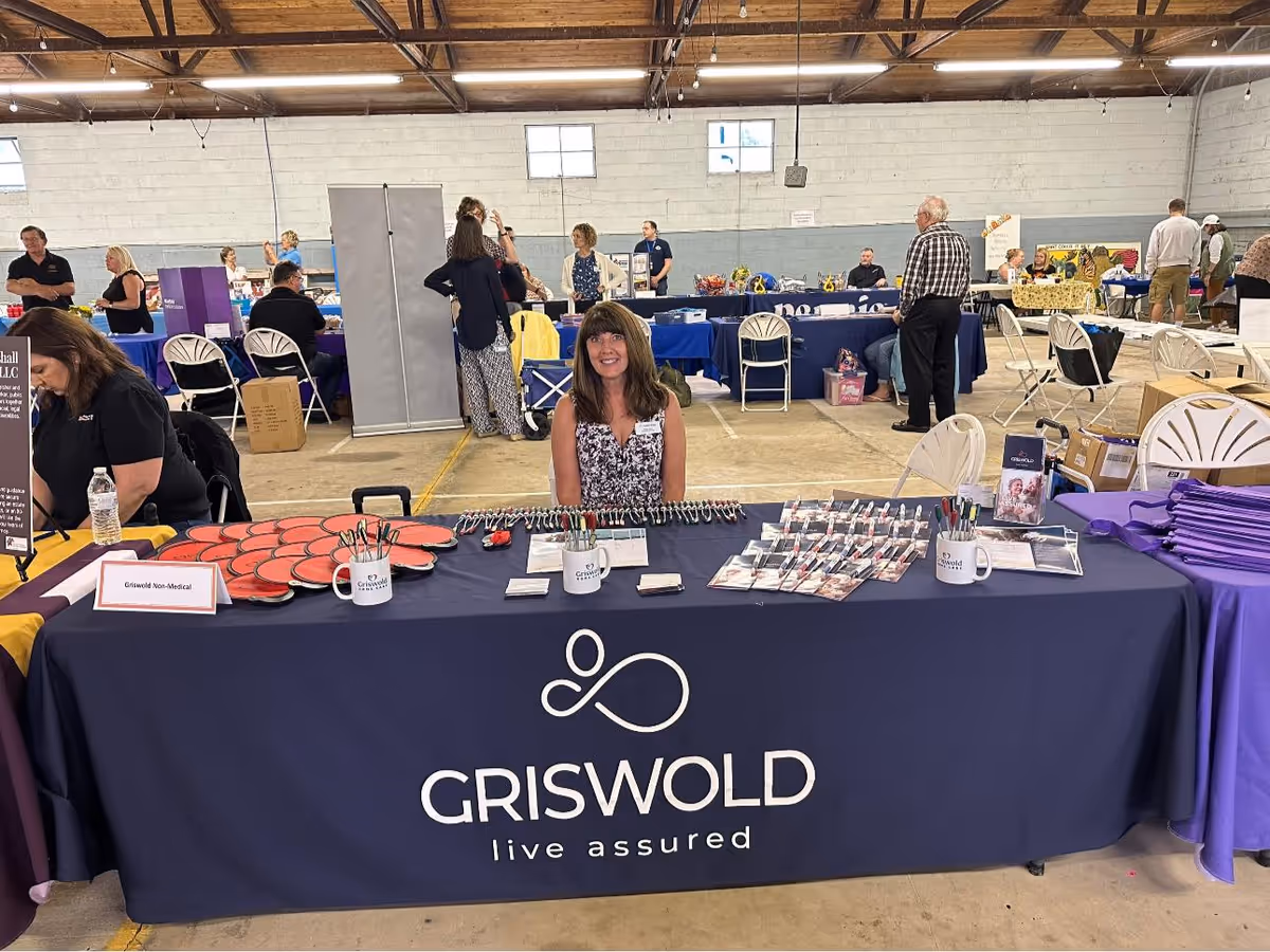 Indoor convention hall featuring a Griswold booth with a long table and attendees.